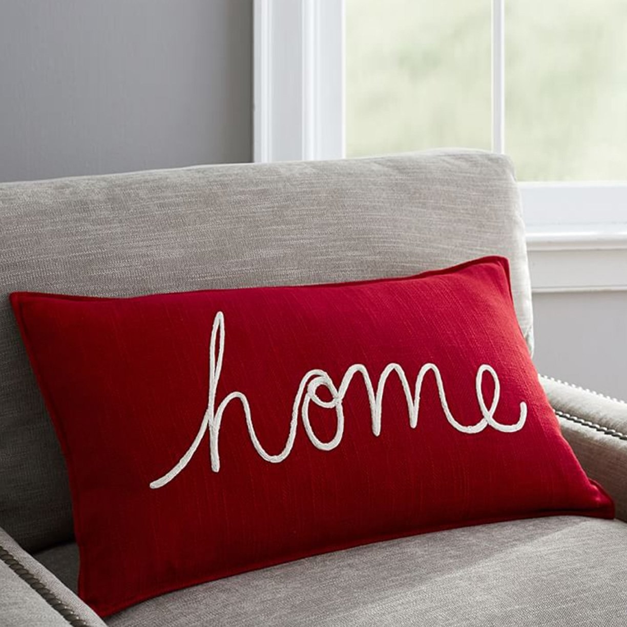A maroon throw cushion with the word &#x27;home&#x27; on it.