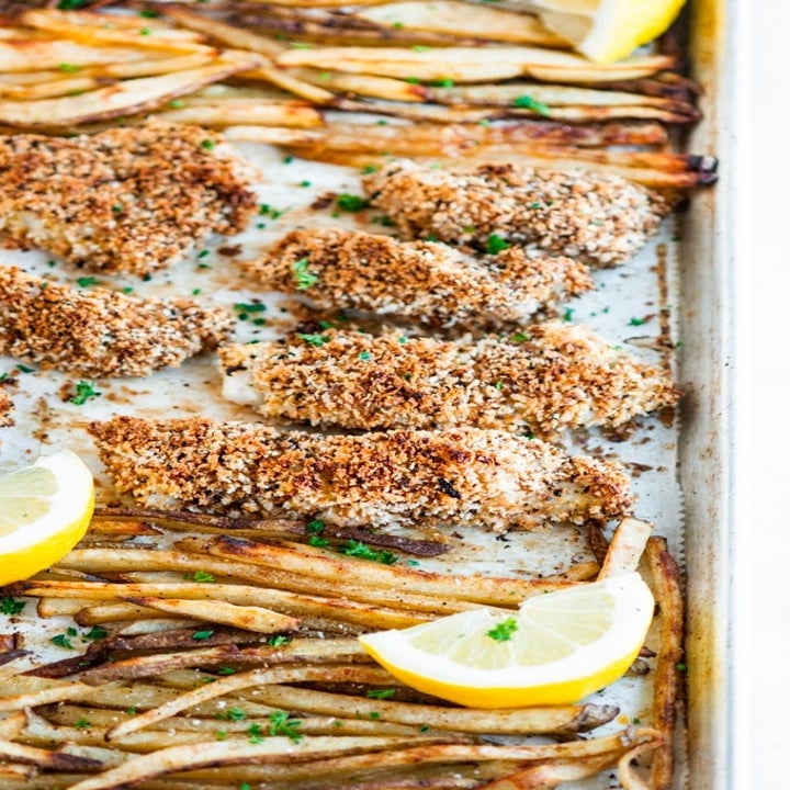 Breaded baked fish sticks and French fries on a baking sheet.