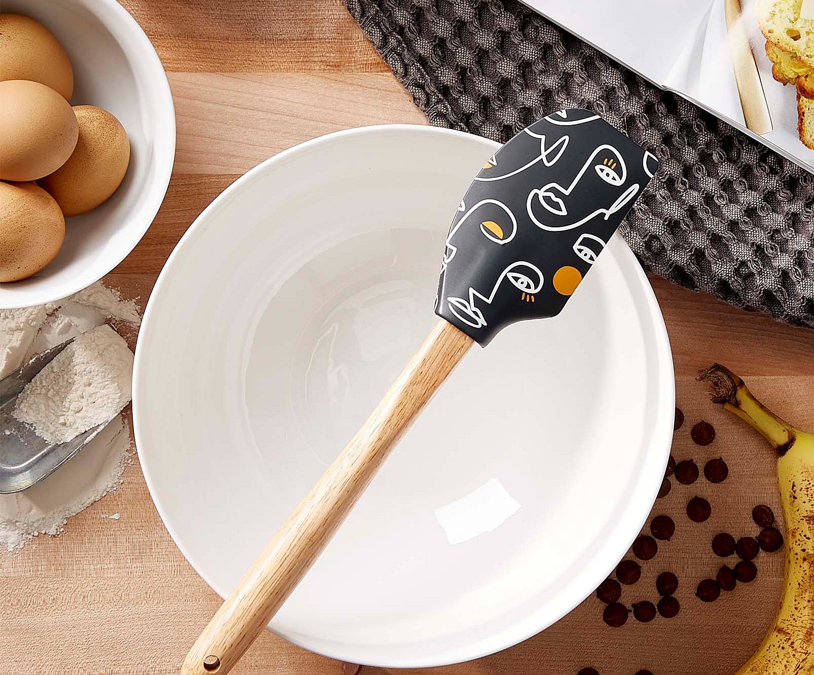 A spatula sitting on top of a large empty mixing bowl