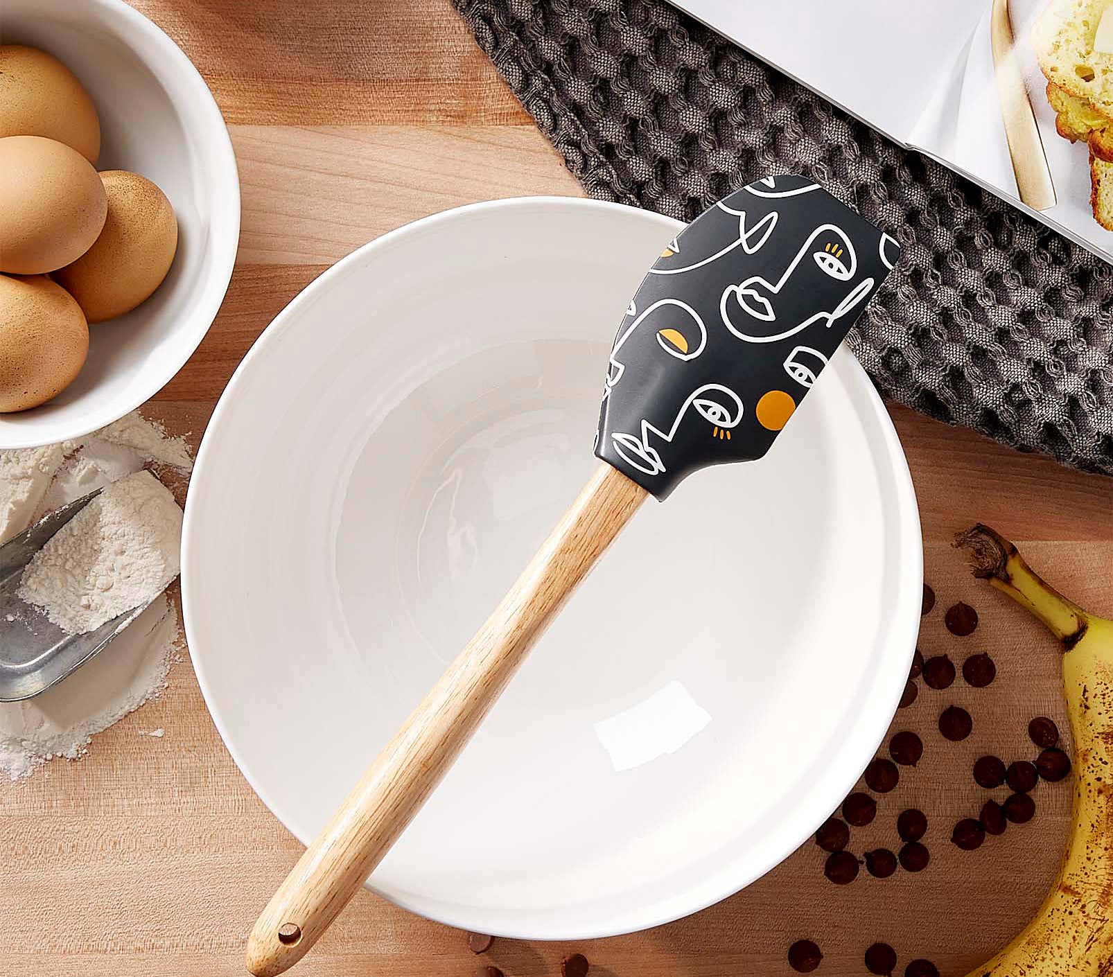 A spatula sitting on top of a large empty mixing bowl