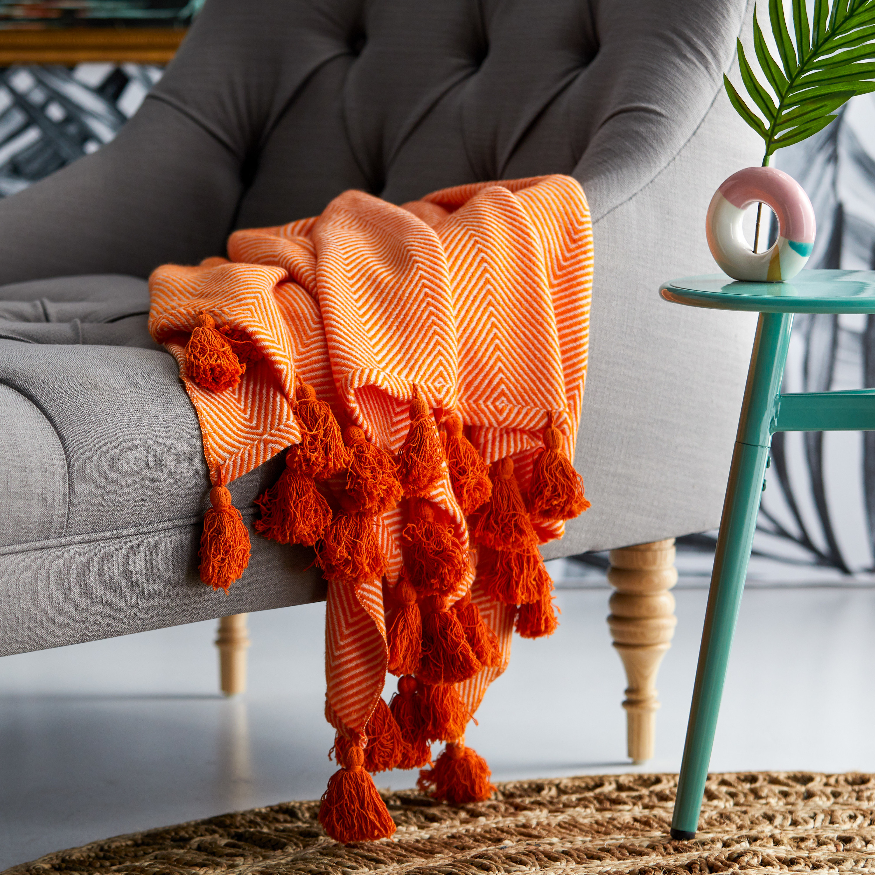 Bright orange blanket with a chevron pattern and large fringe tassels on the ends