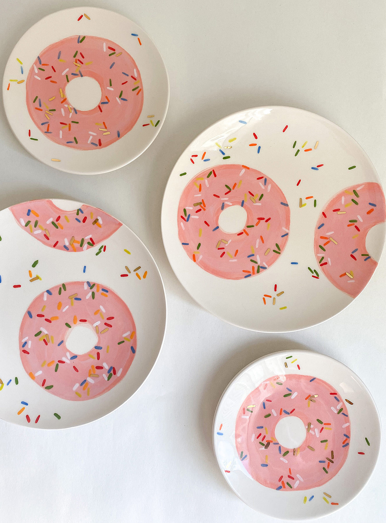 Four ceramic plates with donuts painted onto them