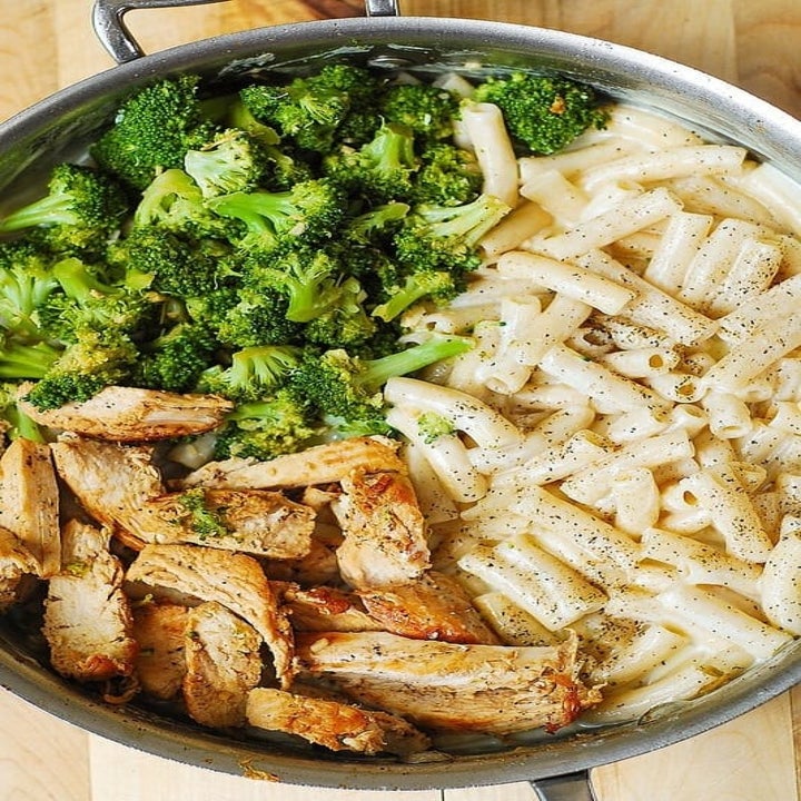 A pot with cooked penne noodles, broccoli, and grilled chicken.