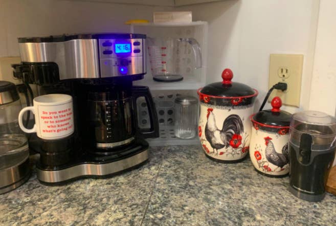 Reviewer uses black two-sided coffee maker to brew coffee in a pot and a funny mug