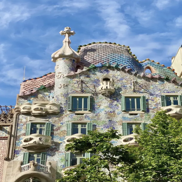 A building with a patterned facade that almost resembles fish scales and has a turret peeking out from the top