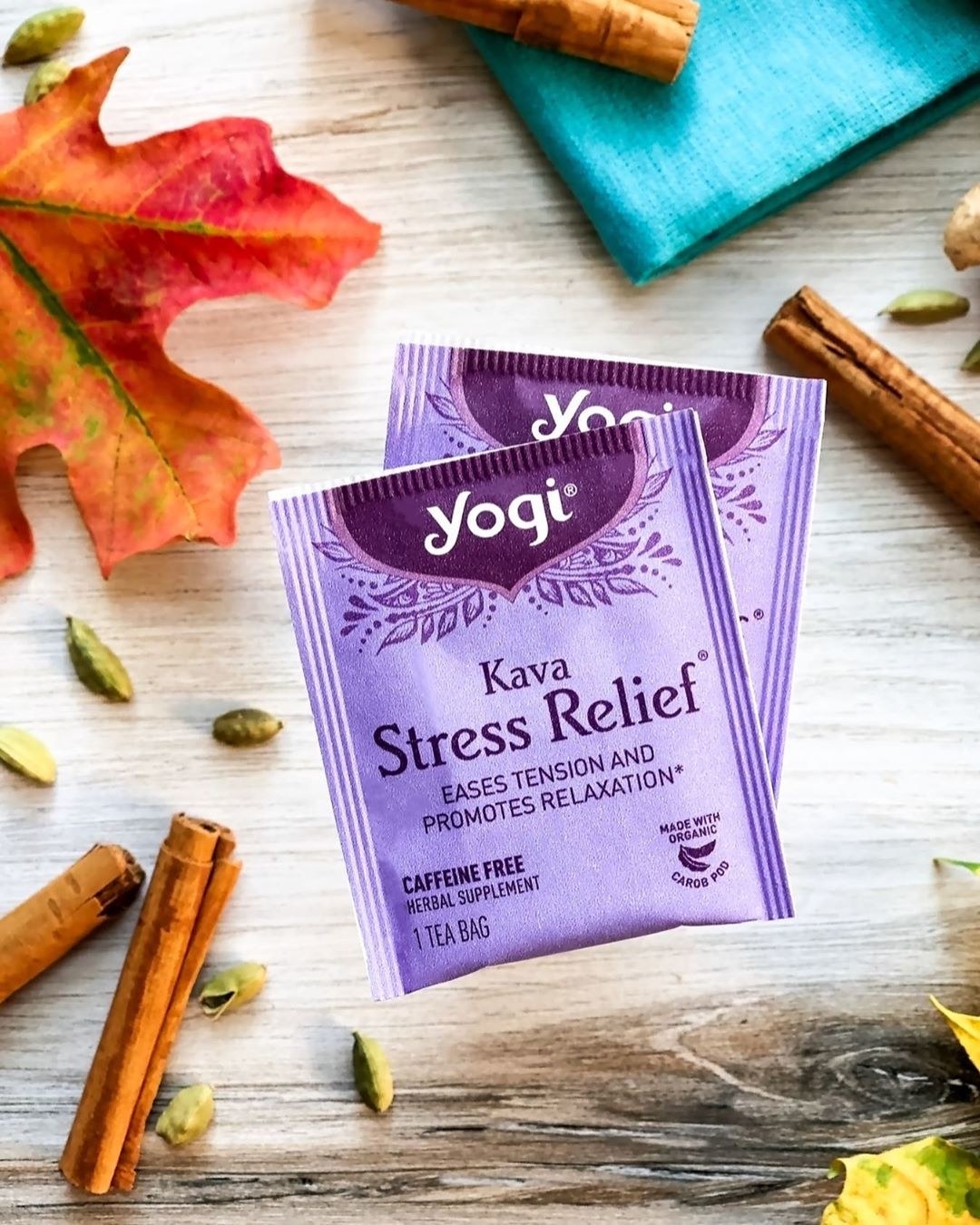 Purple tea bags that say "Yogi Kava Stress Relief" on a wooden table with cinnamon sticks