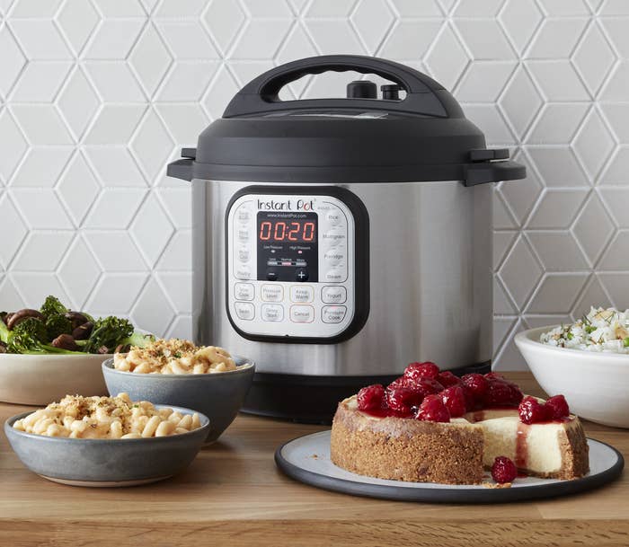 The Instant Pot on a counter with food items that can also be made inside like mac and cheese and cheesecake