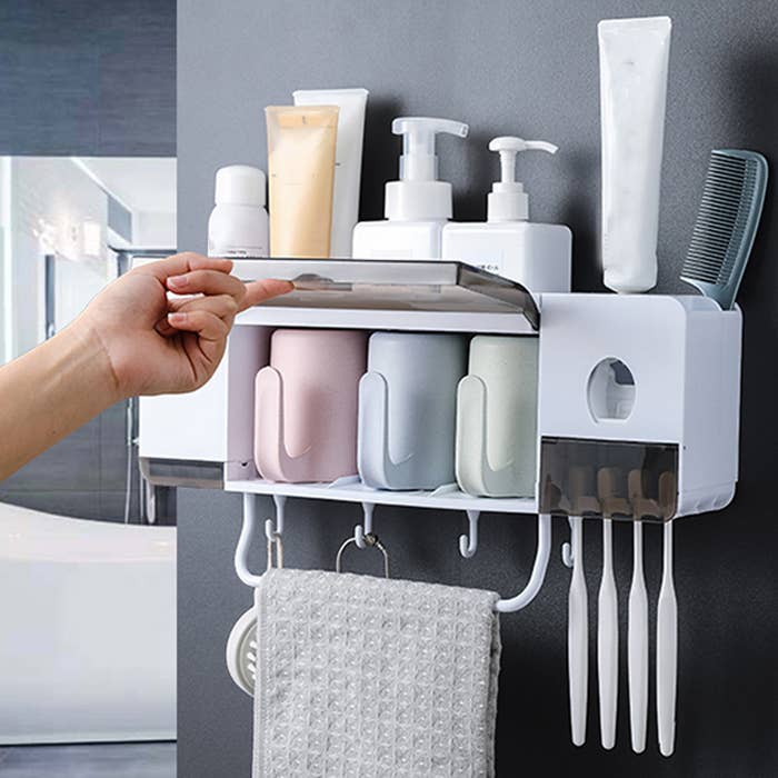 A person opening up the lid on the hanging organize where the cups are stored