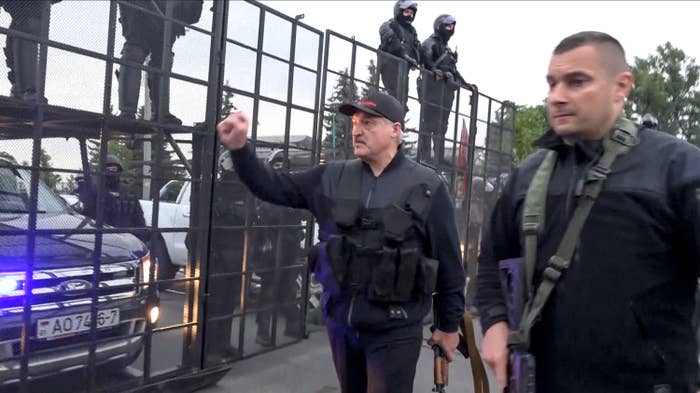 President Alexander Lukashenko carries a rifle while greeting riot police behind a fence