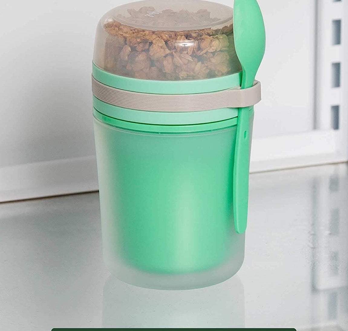 the green yogurt container with an attached green spoon and clear top compartment