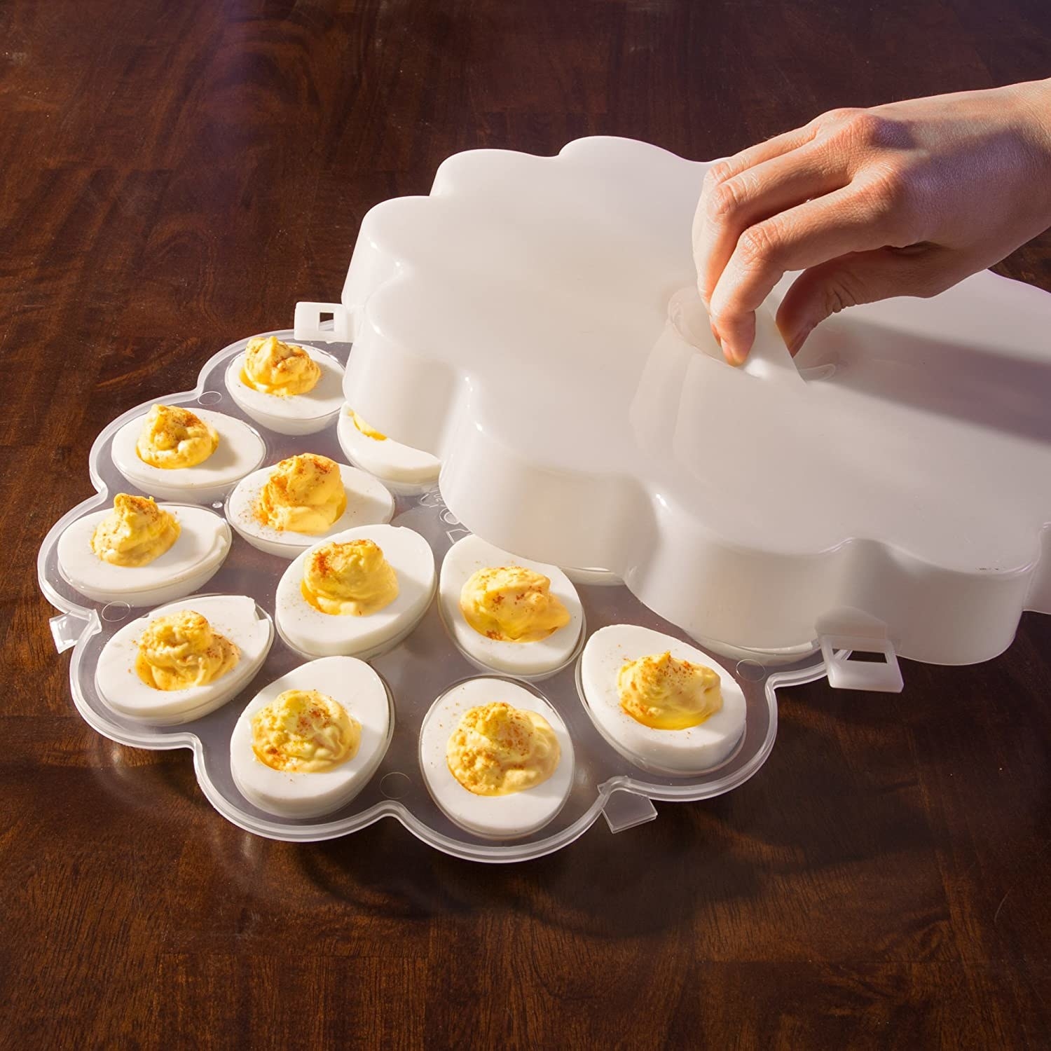 A person lifts the lid of the egg tray to show off a dozen perfectly crafted devilled eggs