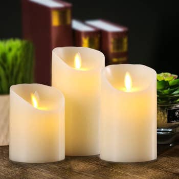 three pillar off white candles with flickering look fake flames