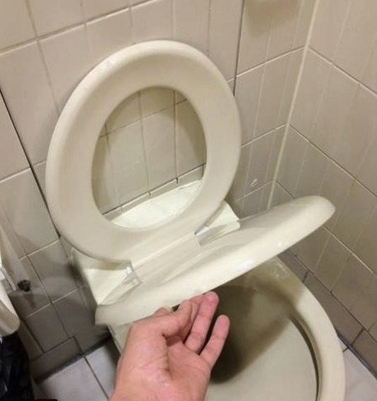 A toilet bowl with the lid underneath the seat