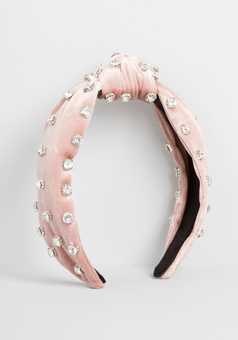 Pink velvet headband with a knot at the top middle with rhinestones embellished all over it