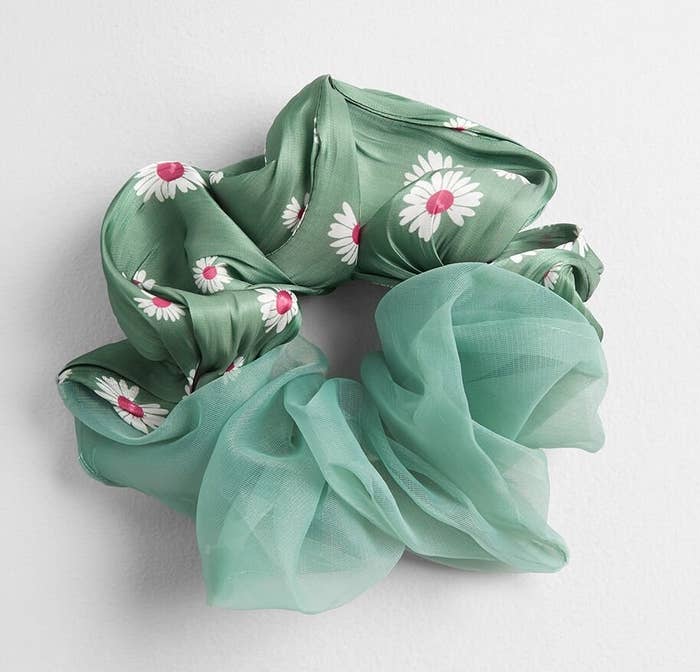 The scrunchie with half a satin-like fabric in sage with white and pink flowers on it and the other half a sheer sage fabric