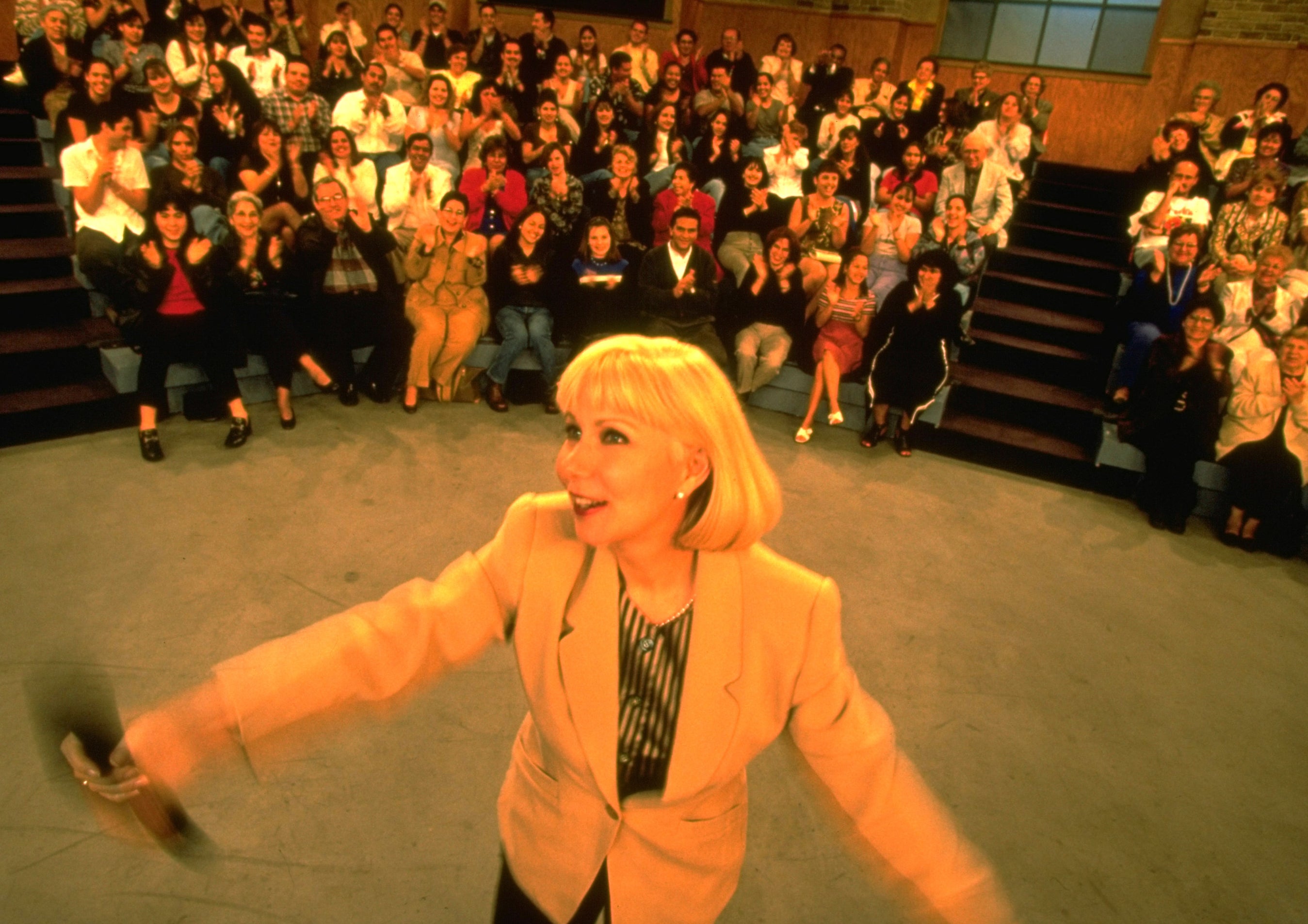 A photo Cristina Saralegui dancing with the audience behind her applauding on the set of her show