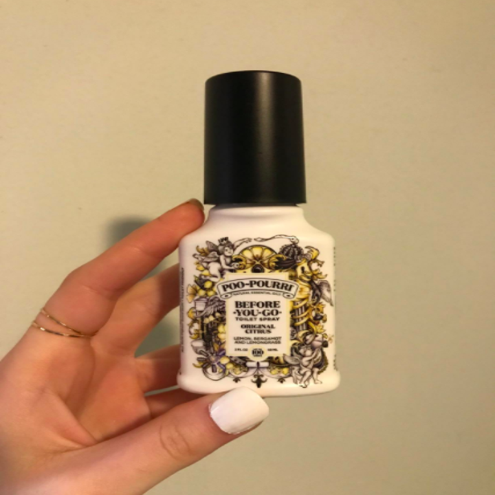 A customer holding a bottle of the 2 oz Citrus poo-pourri toilet spray