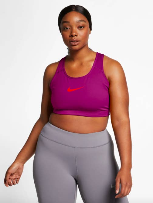 Model wears dark pink Nike Medium Support Sports Bra with gray leggings
