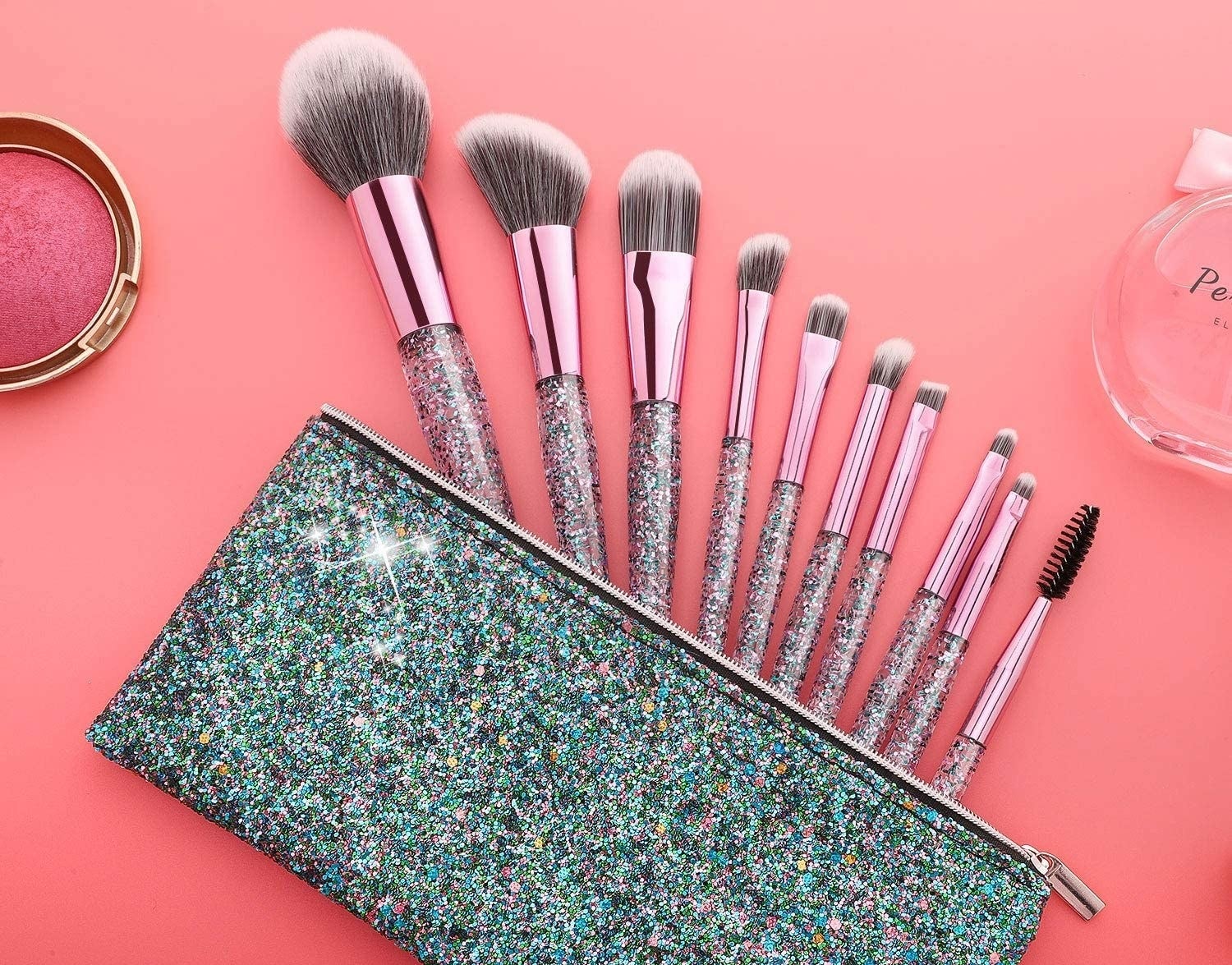 Nine makeup brushes with sparkly handles in a sparkly makeup bag