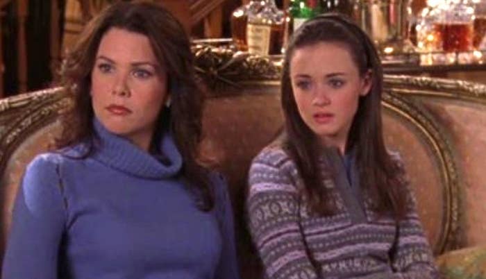 Lorelai and Rory sitting on the couch with bewildered looks on their faces in &quot;Gilmore Girls.&quot;