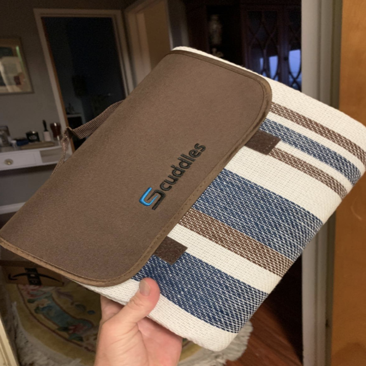 Reviewer holding up blanket rolled up with a carrying handle 