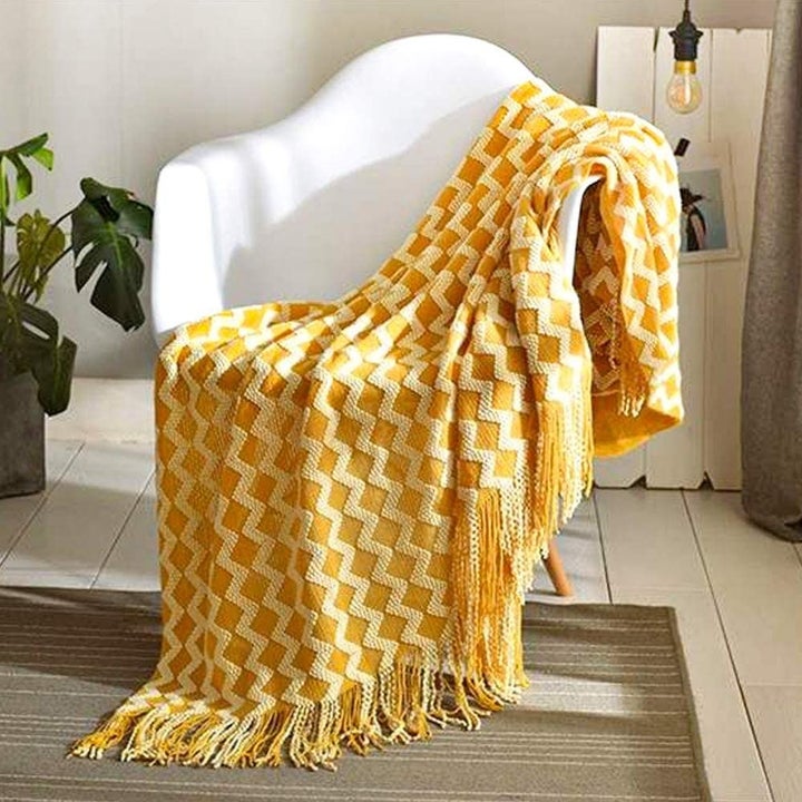 Yellow tasseled blanket with white, three dimensional zigzag pattern