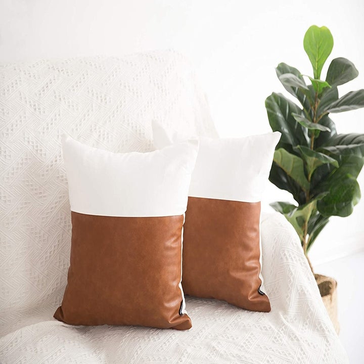 Two decorative pillows with one half white and one half faux leather