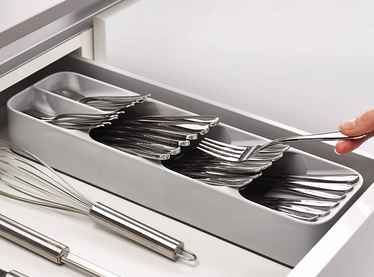 Model&#x27;s fingers removing a fork from a neat stack of utensils in a gray plastic utensil organizer with five sections for knives, spoons, and more