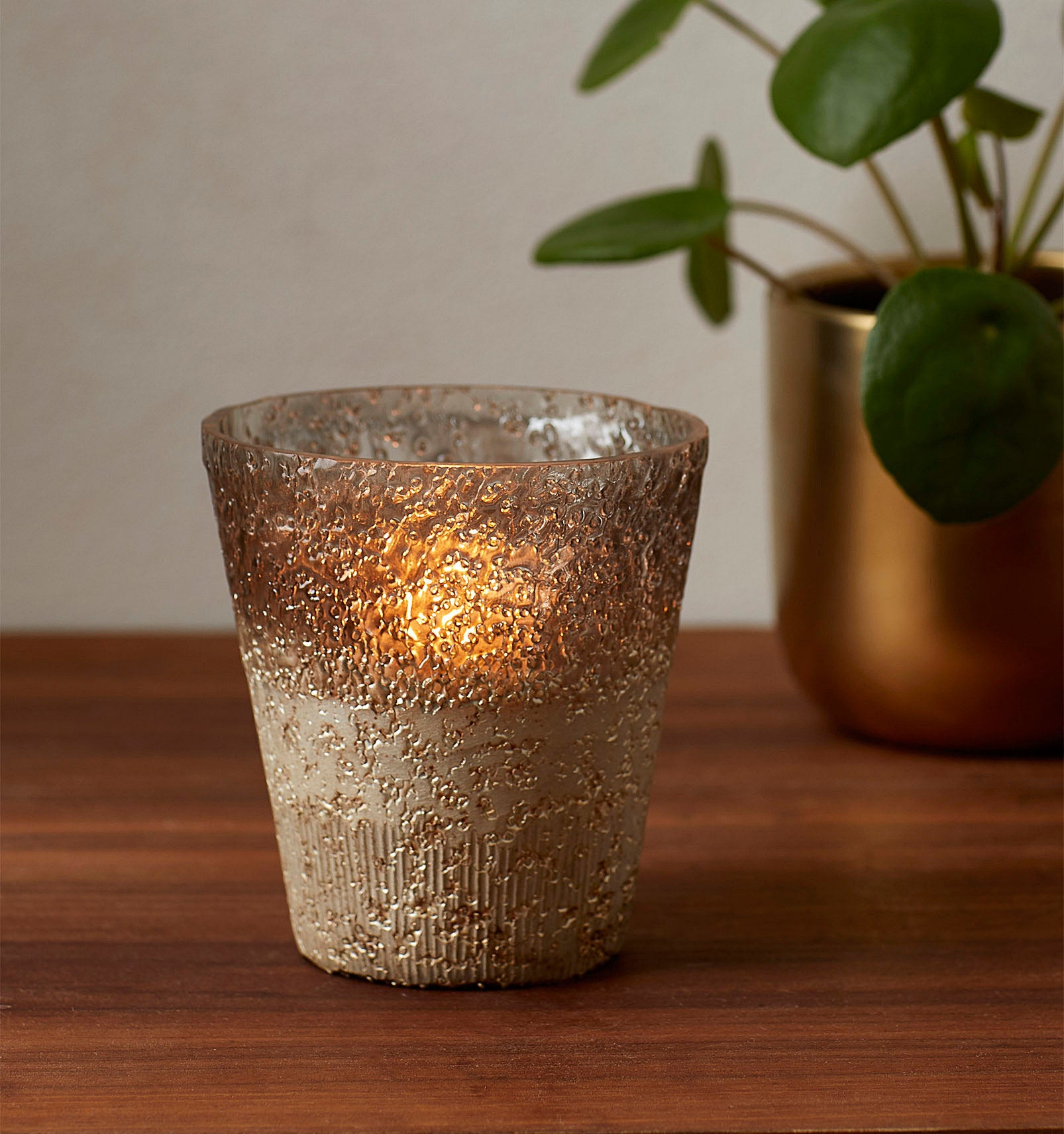 A candle votive is illuminated by a candle