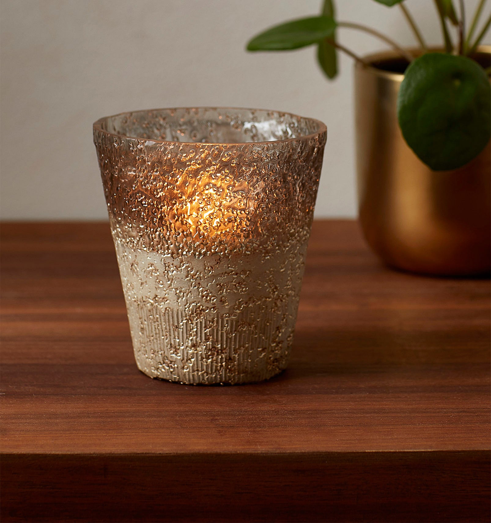 A candle votive is illuminated by a candle