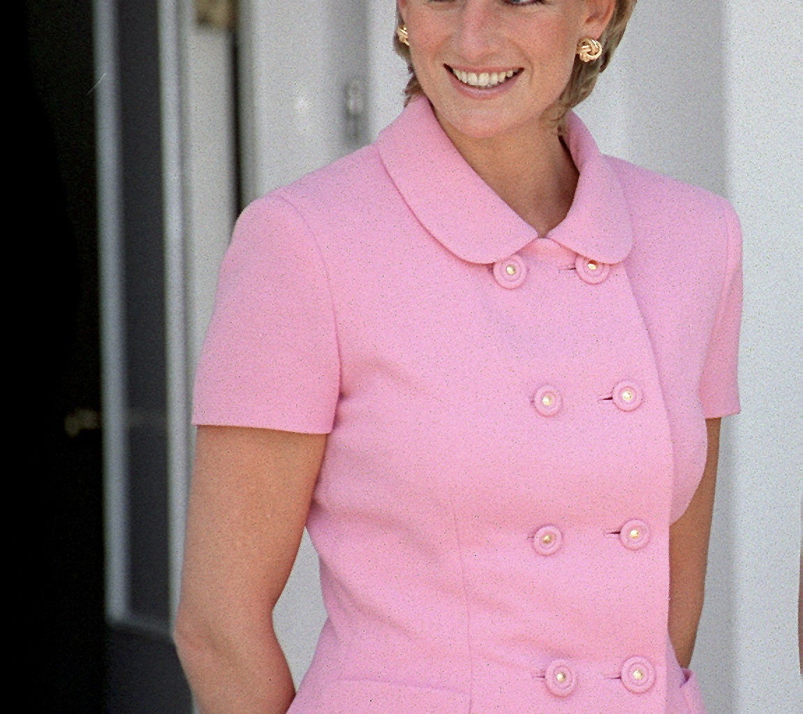 A photo of Princess Diana smiling while wearing a powder pink Versace short sleeve suit