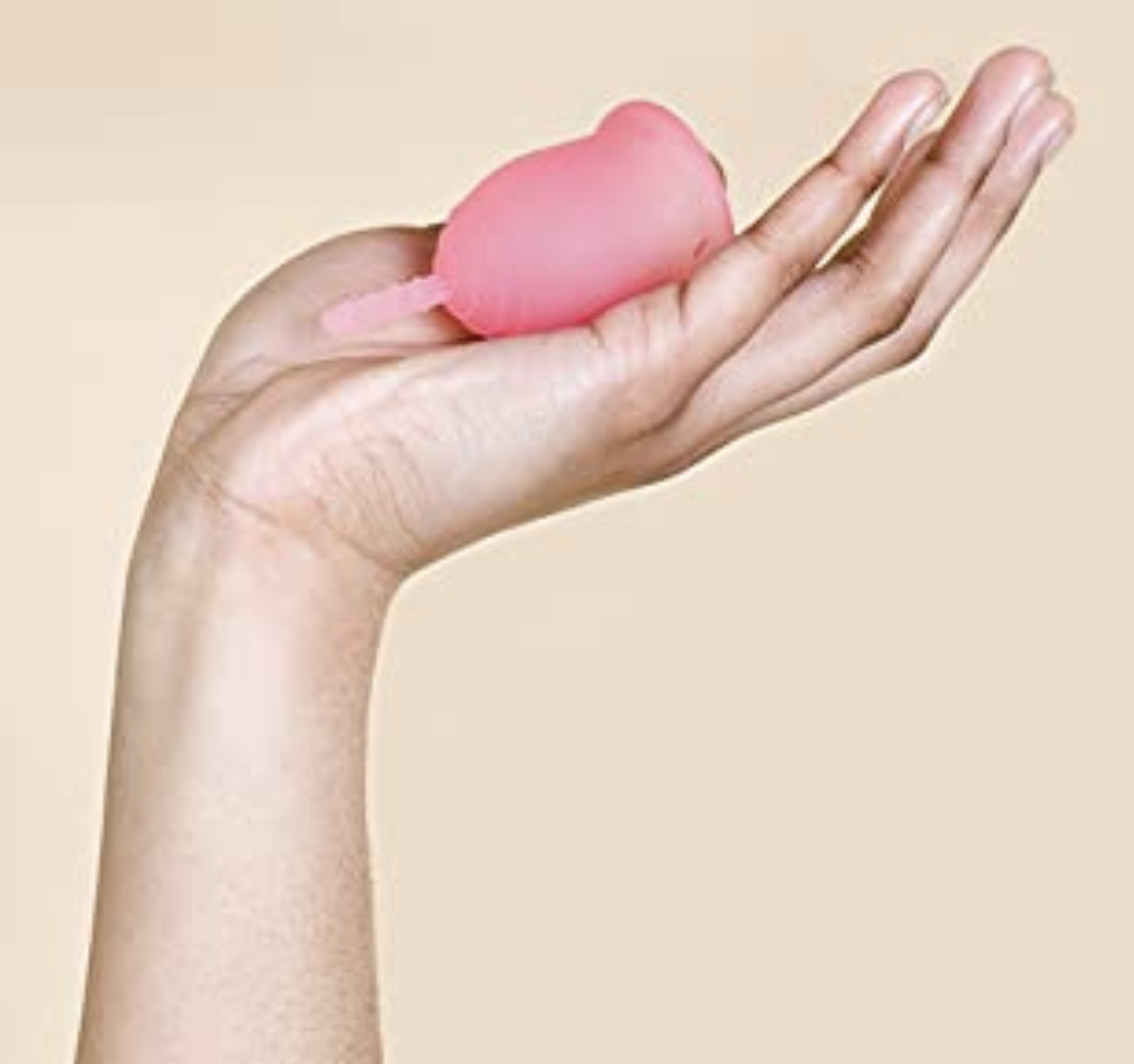 a model holding a pink menstrual cup 