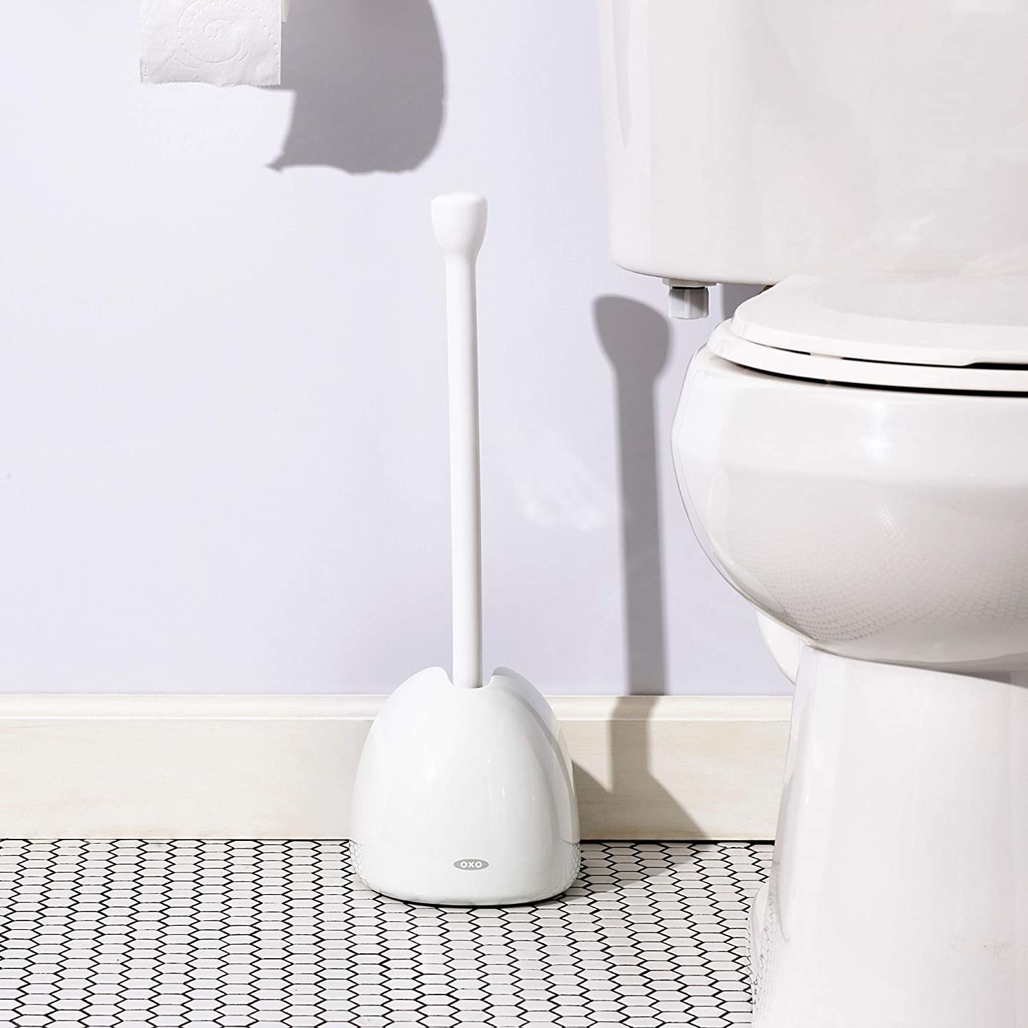The white OXO Good Grips Toilet Plunger with Cover next to a toilet