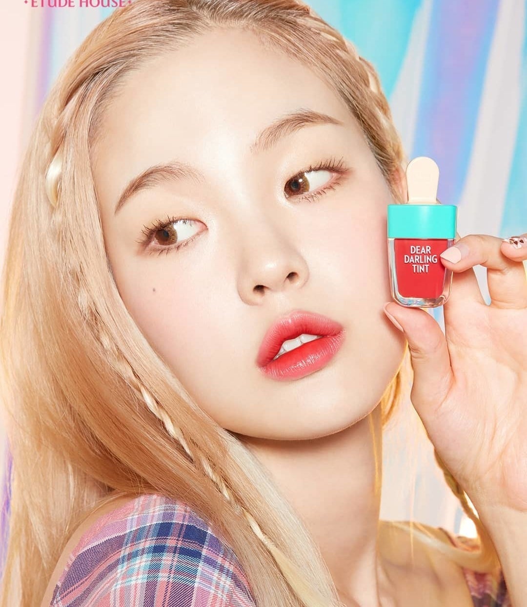 A person holds a lip tint that looks like a popsicle with a tint on their lips