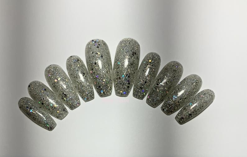A set of press on nails in different sizes to correspond to actual fingerprint sizes filled with sparkles