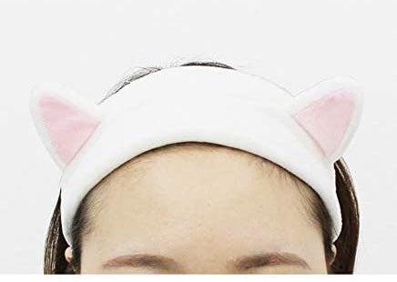 A person wears a headband with cat ears to keep their hair from their face