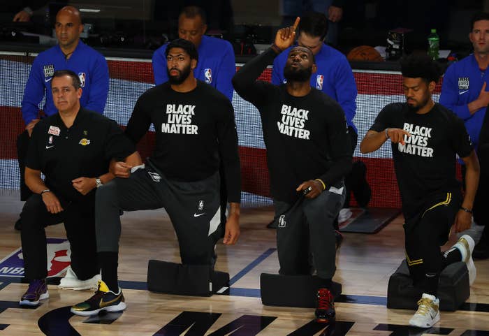 Players wearing &quot;Black Lives Matter&quot; T-shirts kneel at a basketball court