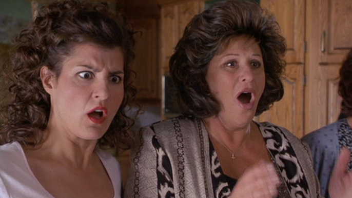 Toula and Maria looking at something offscreen with shocked expressions on &quot;My Big Fat Greek Wedding.&quot; 