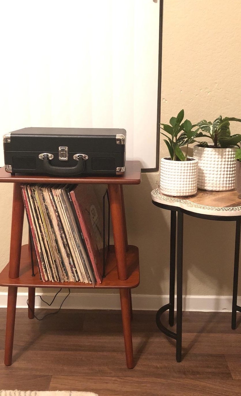 Reviewer pic of the brown wood two-tier stand with black wire slots in the middle holding vinyl records and a record player on top