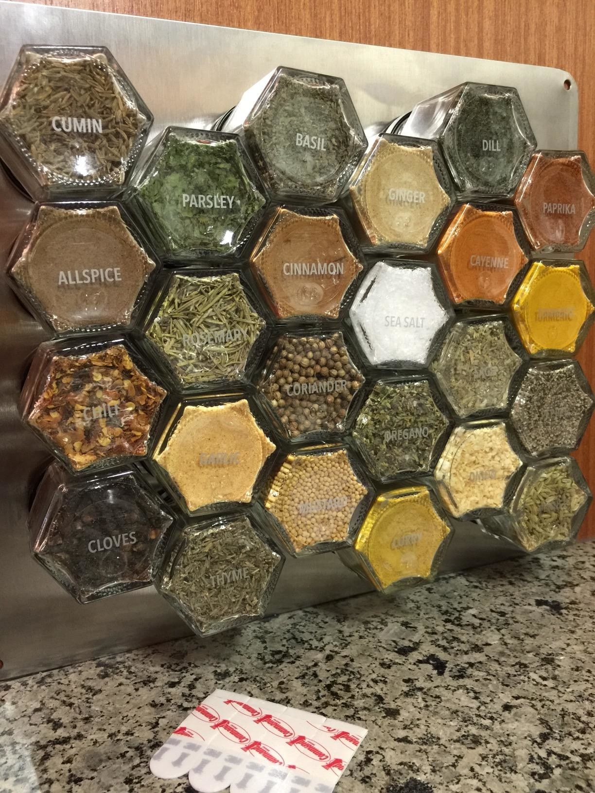 Hexagonal spice jars attached to a magnetic wall-mounted metal plate