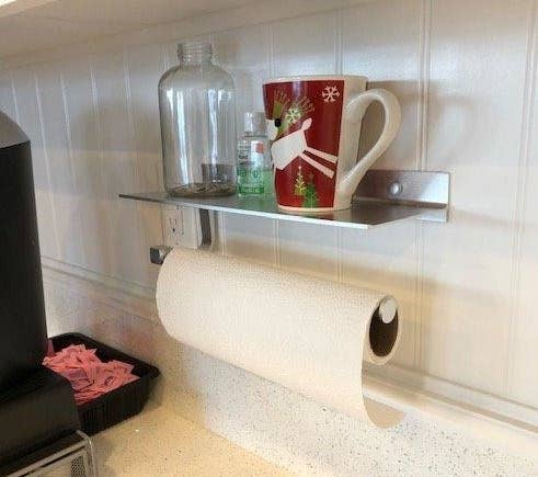 Aluminum paper towel holder with small shelf mounted to wall 