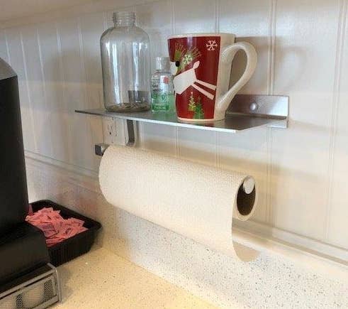 Aluminum paper towel holder with small shelf mounted to wall 
