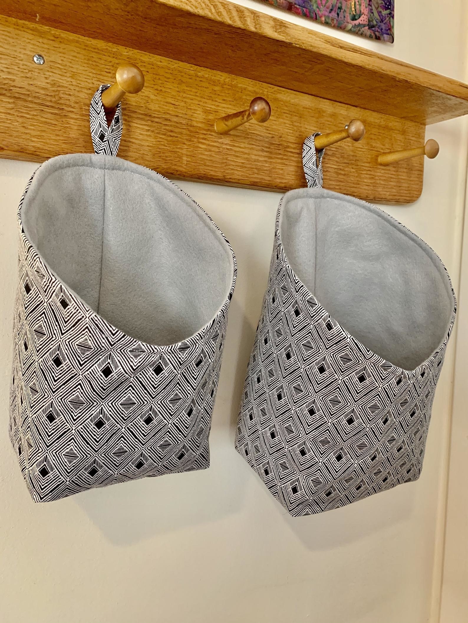 Two patterned fabric storage pods hanging from kitchen hooks