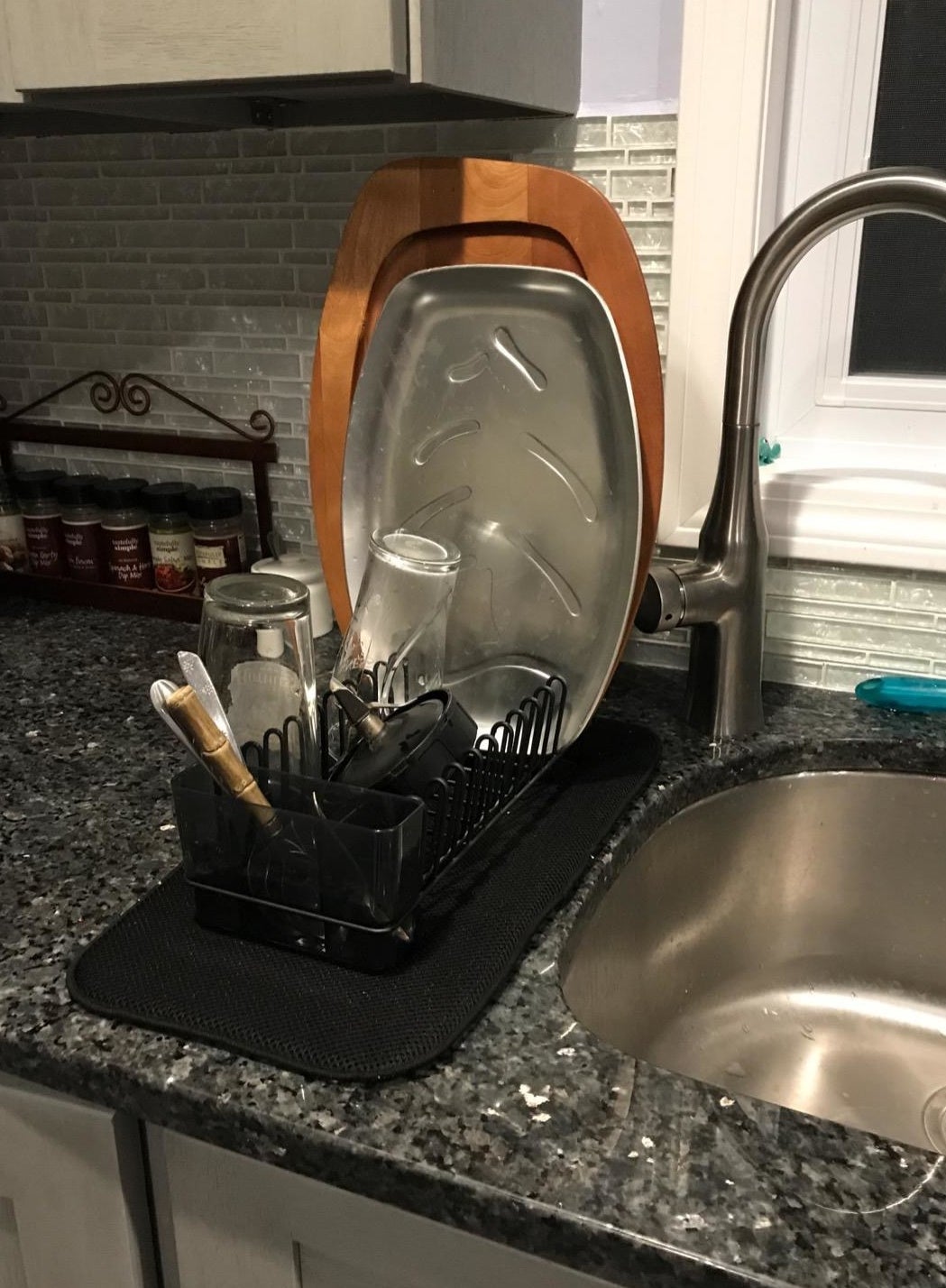 Reviewer picture of the small dish drying rack with the black mat under it with assorted dishes in it next to a sink