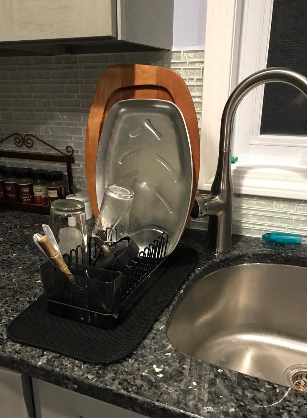 Reviewer picture of the small dish drying rack with the black mat under it with assorted dishes in it next to a sink