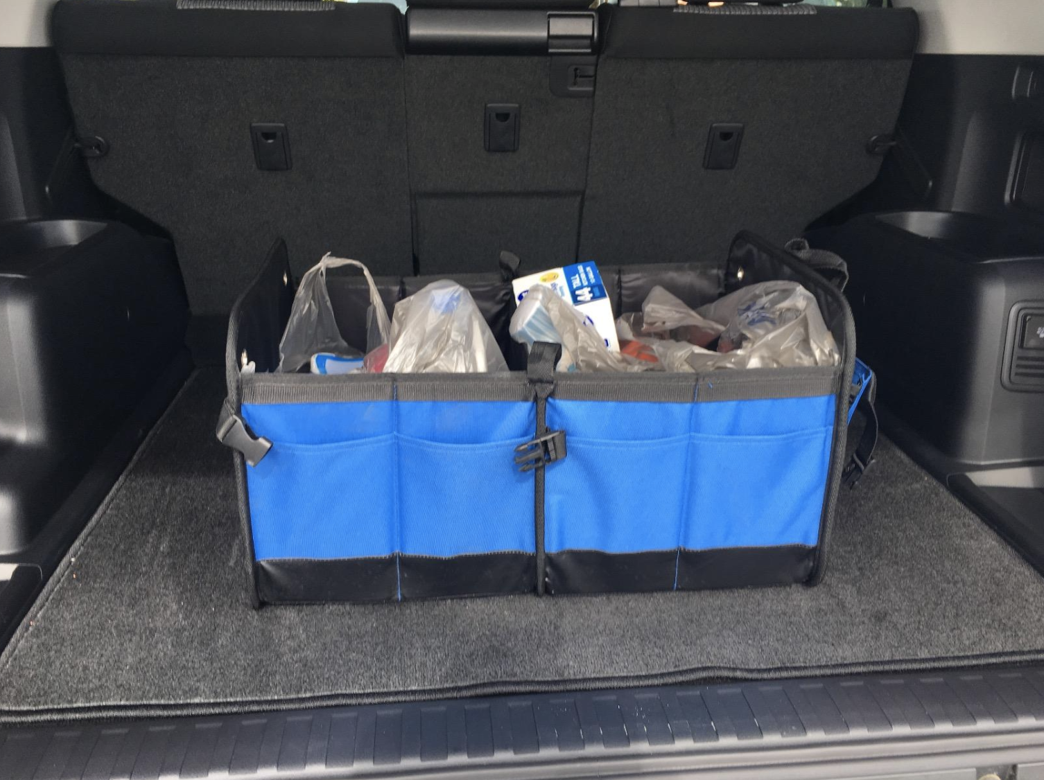 Reviewer image of the blue organizer in trunk holding various groceries
