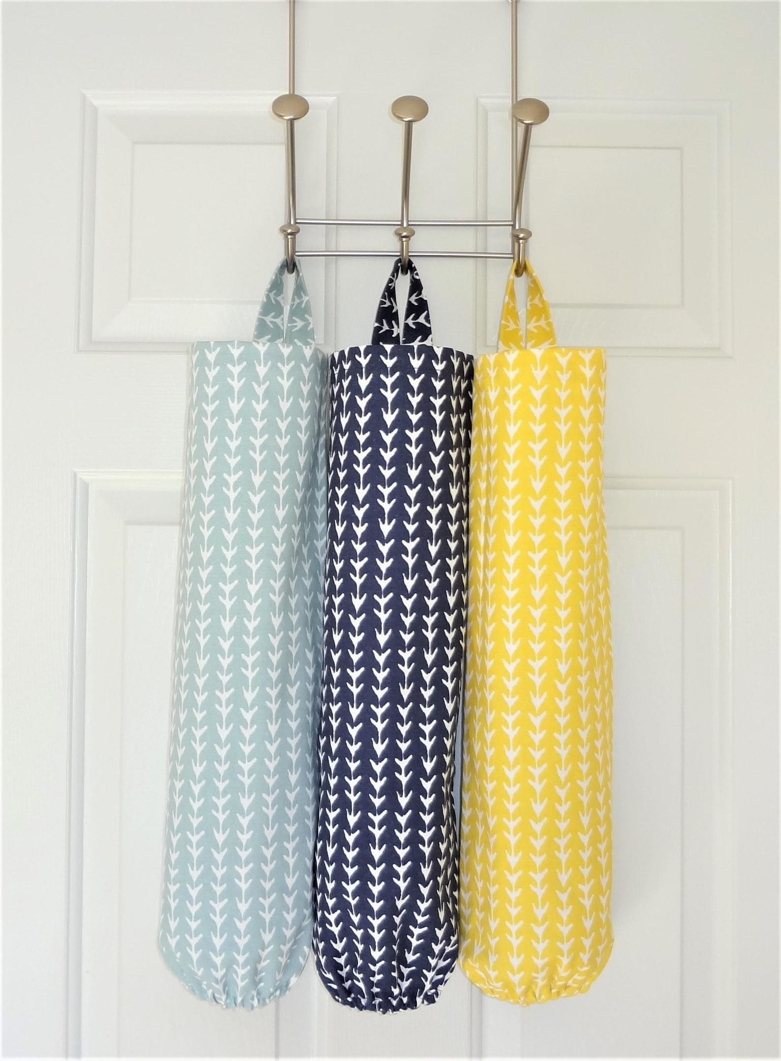 Light blue, navy, and yellow bag holders hanging from hooks on a door