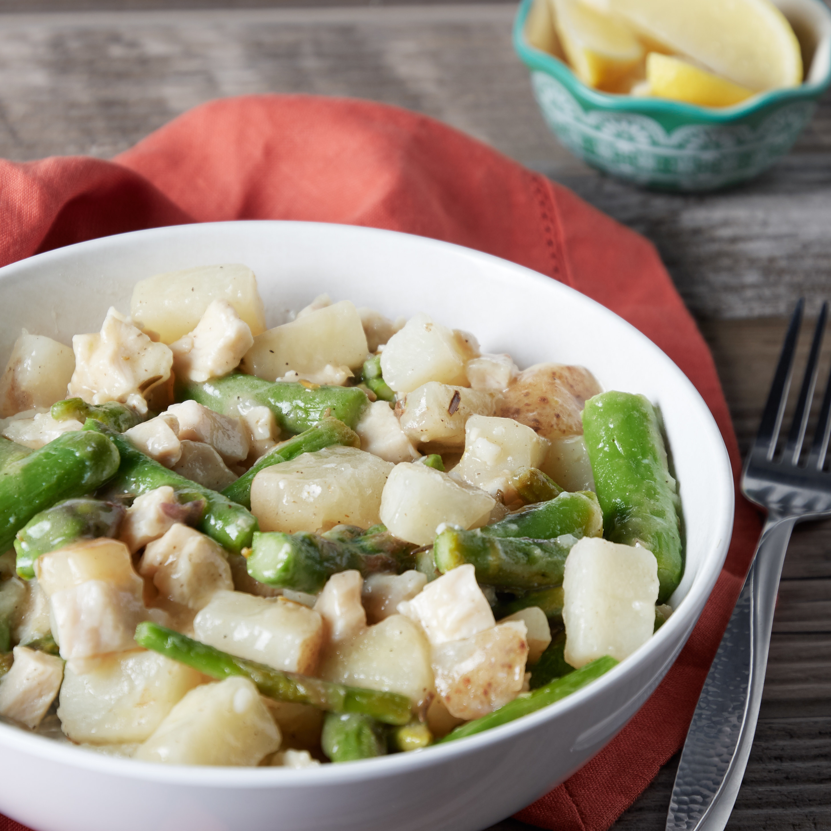 A bowl of cooked chicken pieces and sliced asparagus 