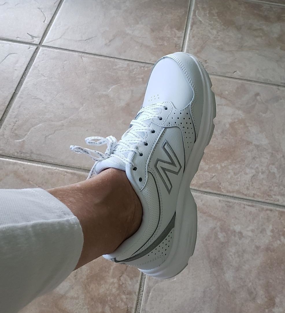 A reviewer showing the white New Balance sneaker with gray accents on their foot