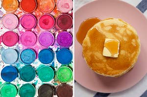 On the left, various watercolor paints, and on the right, a stack of pancakes topped with maple syrup and a pat of butter
